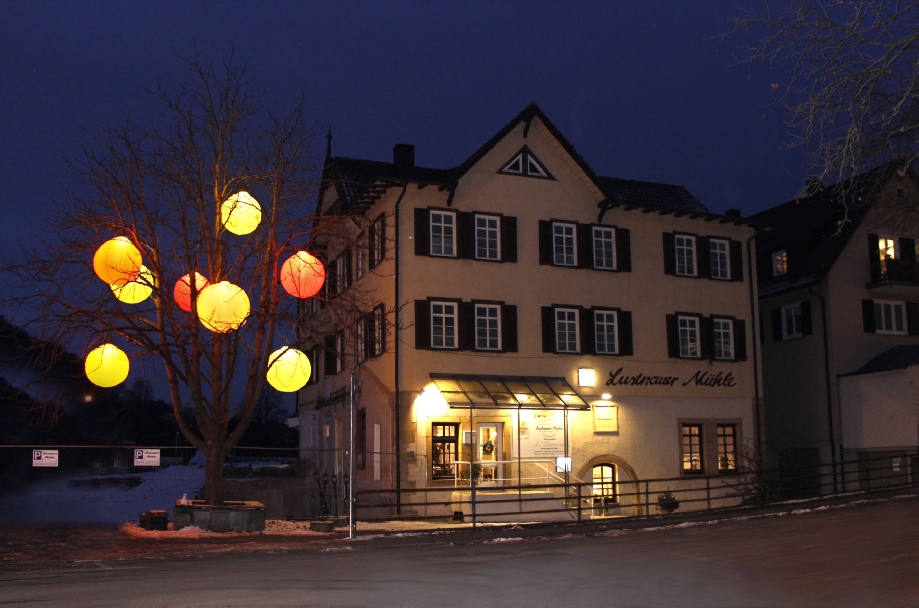 Die Lustnauer Mühle bei Abenddämmerung mit beleuchtetem Vorplatz